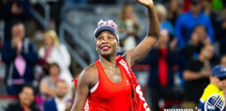 Wearing a red EleVen outfit, Venus Williams waves to the crowd at the 2023 National Bank Open