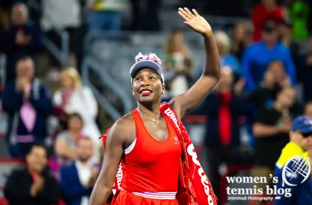 Wearing a red EleVen outfit, Venus Williams waves to the crowd at the 2023 National Bank Open